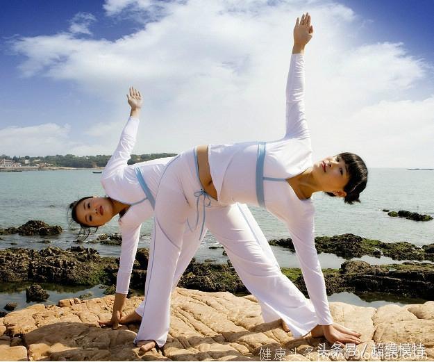 海边石崖上的双人瑜伽