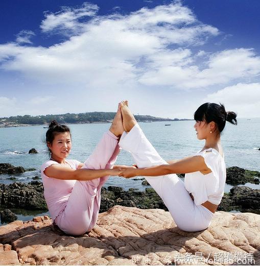 海边石崖上的双人瑜伽